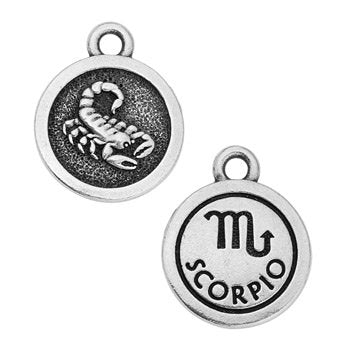 Round pewter zodiac charm in a closer crop, with a scorpion design on one side and the Scorpio glyph on the other