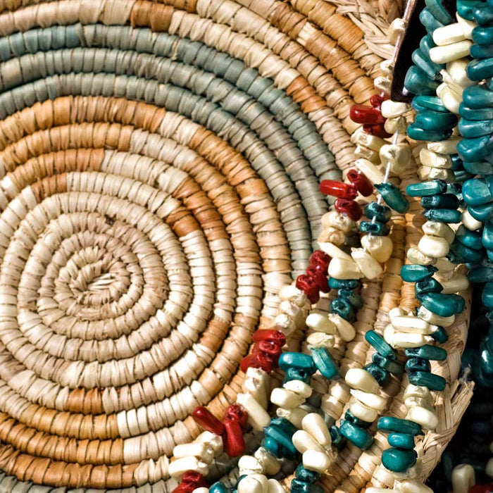 Woven coiled basket with turquoise, red and white bead strands, a traditional craft use for sinew