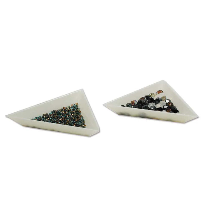 Side angle of two white triangular trays holding small seed beads and larger faceted beads in mixed dark colors