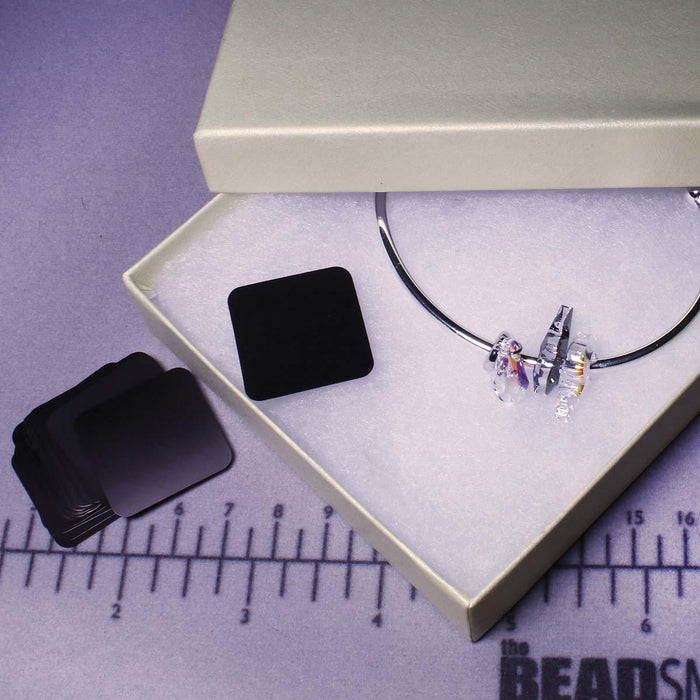 Anti-tarnish tabs beside an open white gift box with a silver bracelet, on a ruler mat showing size