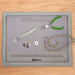 Top view of flocked bead mat tray on a wood table with pliers, beads, findings and beaded necklace on the ruler mat