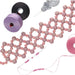Beading needle and threader beside thread spools and a pink beaded flower-pattern bracelet project