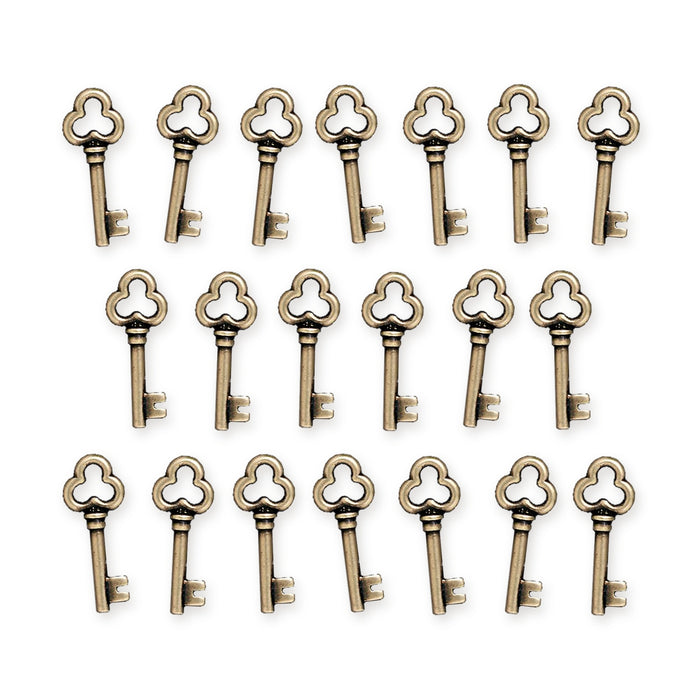 Antiqued brass key charms with trefoil bows arranged in three rows on a white background