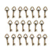 Antiqued brass key charms with trefoil bows arranged in three rows on a white background
