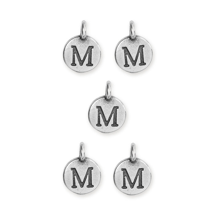 Antiqued silver letter M charms, five round pewter discs with loops arranged in a pattern on white