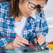 Woman wearing the clip-on LED magnifier on her glasses while soldering a circuit board