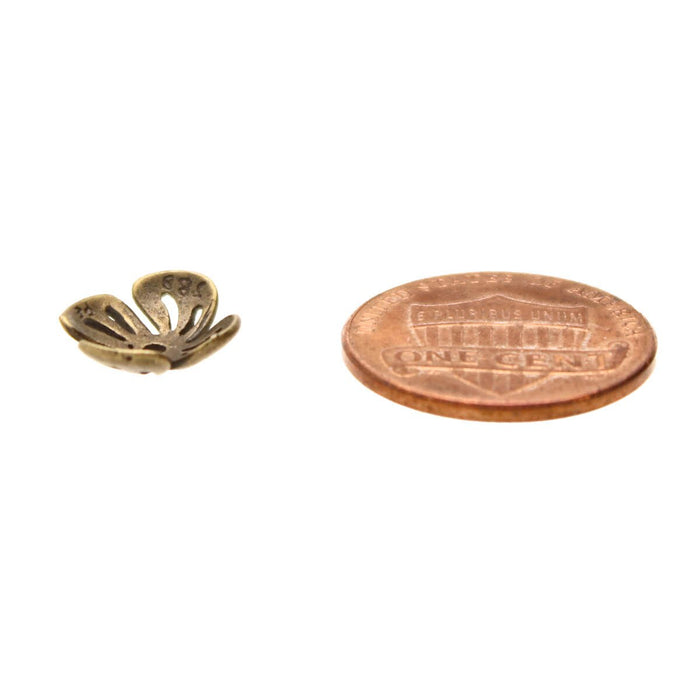 Side view of an antiqued brass flower bead cap next to a US penny for size comparison