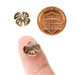 Antiqued brass flower bead caps held on a fingertip and next to a US penny to show their small size