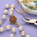 French wire styled with pearl necklace, flower clasp, glass beads in a dish and BeadSmith pliers on a purple surface