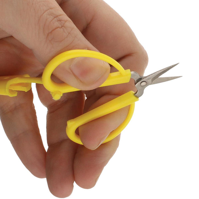 Hand holding the yellow mini scissors to show the small 2.5 inch size and finger loops