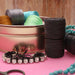 Black S-Lon nylon cord spools beside a rhinestone bracelet, turquoise beads and other colored spools in a tin