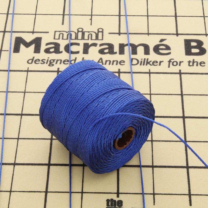 Blue nylon bead cord spool with loose cord strands on a mini macramé board