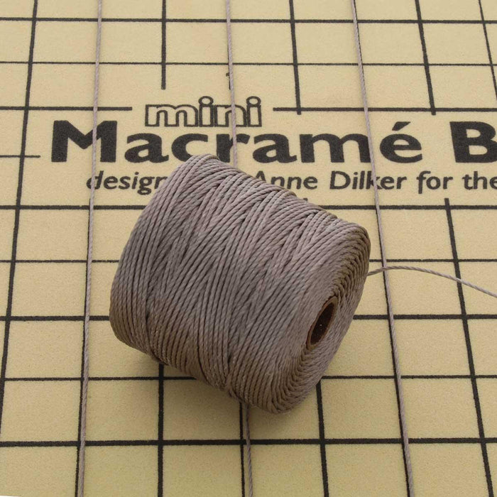 Cocoa nylon bead cord spool resting on a mini macramé board with cord strung across the grid