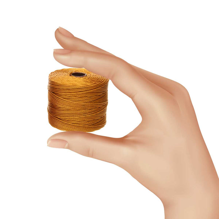 Hand holding a spool of gold S-Lon nylon bead cord to show its small size