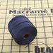 Navy blue nylon bead cord spool with loose end resting on a mini macramé board with grid