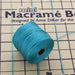 Teal S-Lon nylon bead cord spool resting on a mini macrame board with cord strands pinned across it