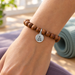 Antiqued silver Buddha coin charm on a sandalwood mala bracelet, design idea