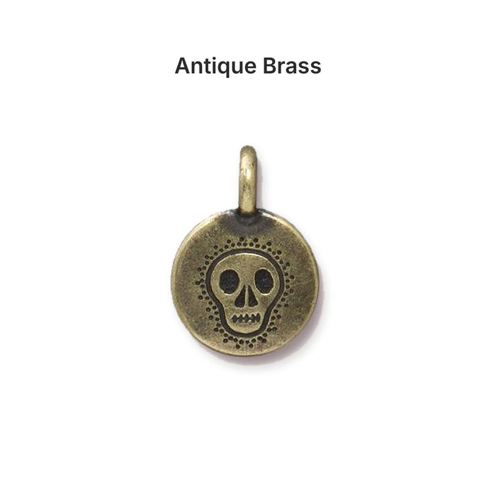Antiqued brass skull coin charm, front