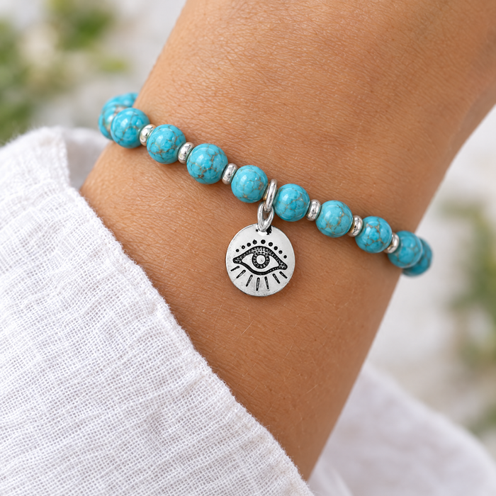Antiqued silver evil eye coin charm on a turquoise blue bead bracelet, design idea